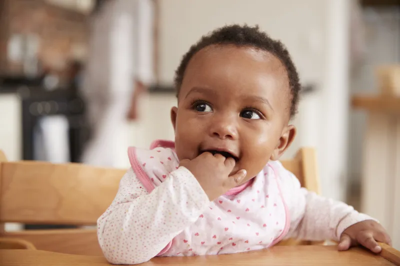 cute baby girl wearing bib sitting in high chair