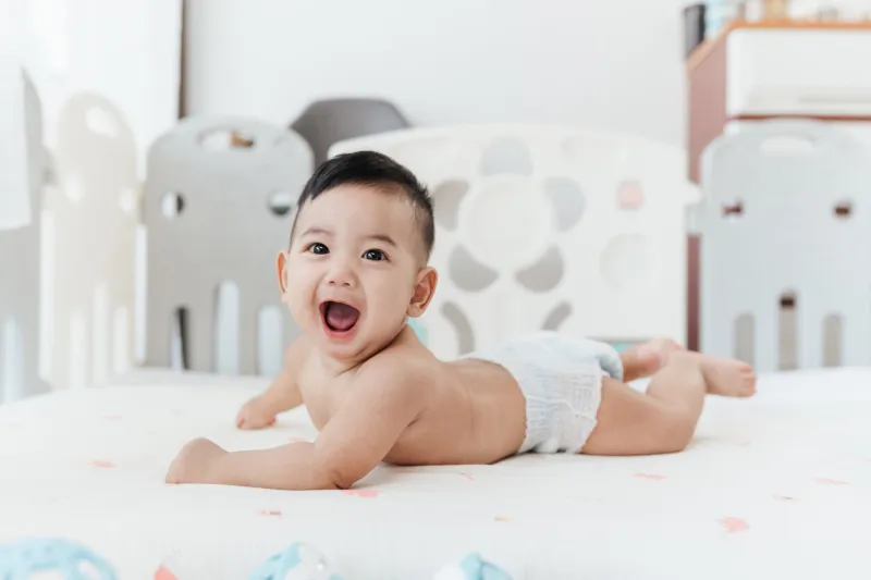 happy asian baby start to crawling on a bed at home, adorable development 5 months old baby healthcare hygiene concept