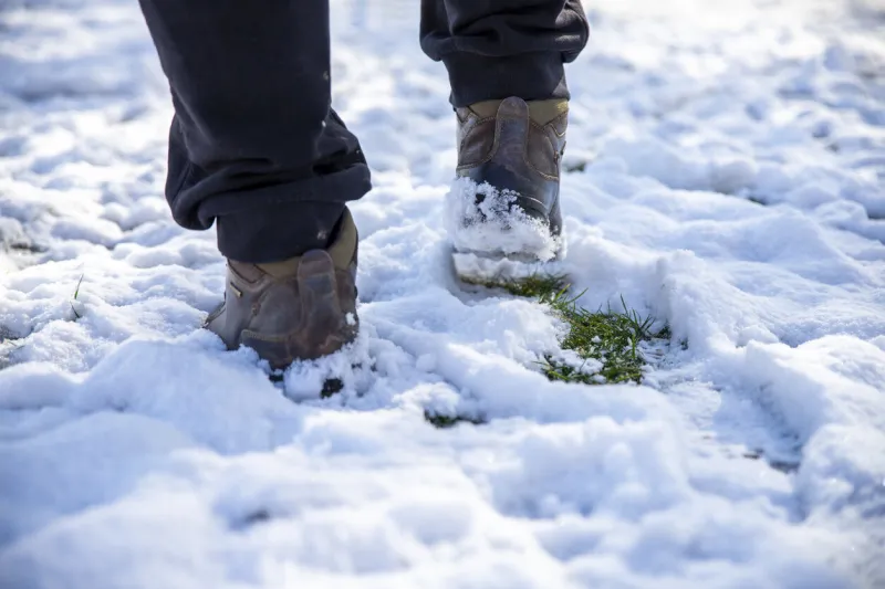 low section of man walking on snow close up men's feet in boots in the snow walking in winter