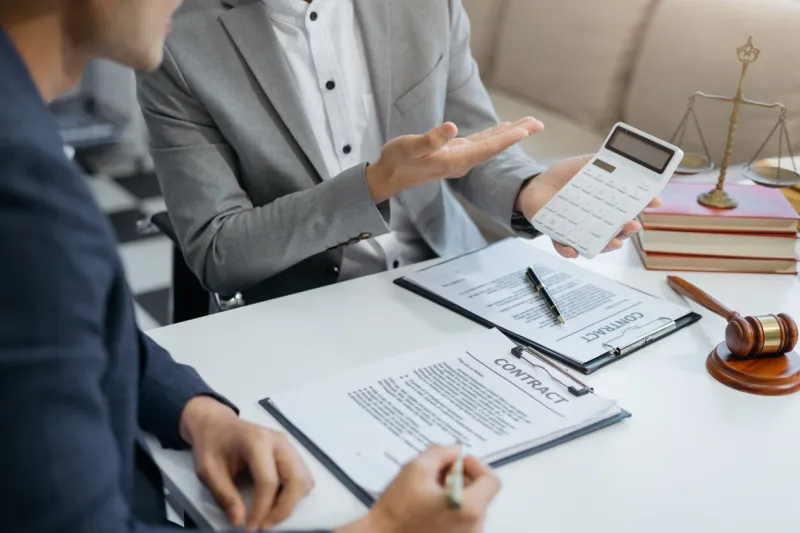 lawyer or accounting department writes a note and uses a calculator to calculate expenses - income at office lawyer