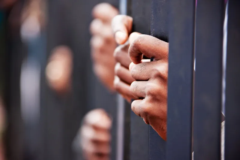 stolen life, group of hands african people behind bars holding them