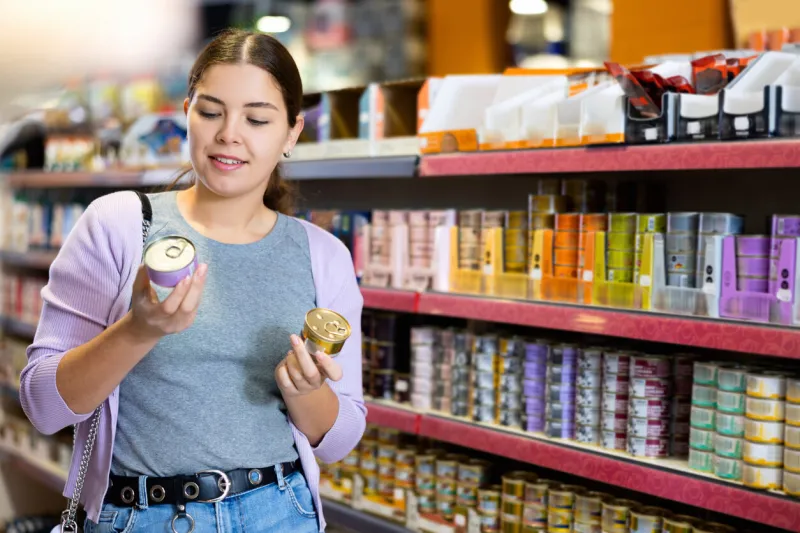 young female customer picking out canned pet food in pet store