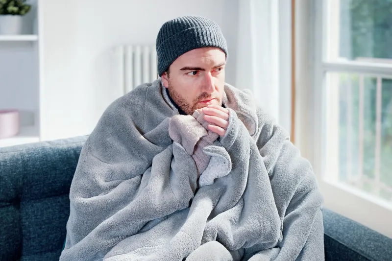 man suffering cold at home and problem with house heating