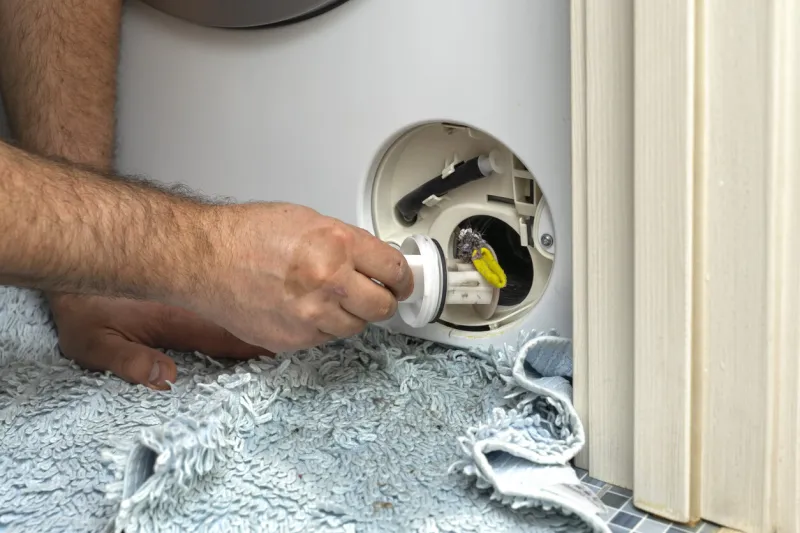 inspecting washing machine's dirty clogged drain pump filter close up, clean and repair