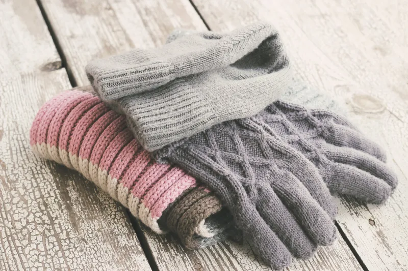 warm winter knitted clothes - hat, scarf, gloves on a wooden background, female, selective focus, vintage toning