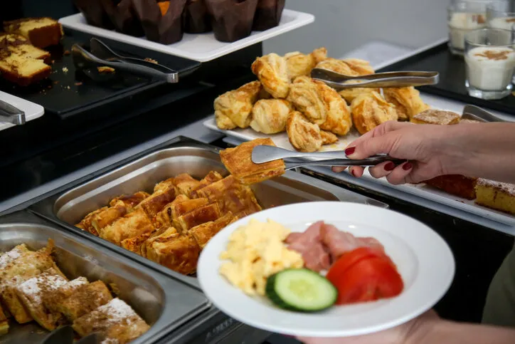 woman taking food from a buffet line
