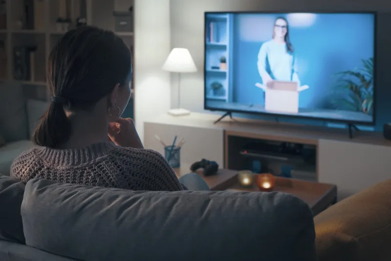 woman relaxing on the couch and watching an unboxing video online on her smart tv