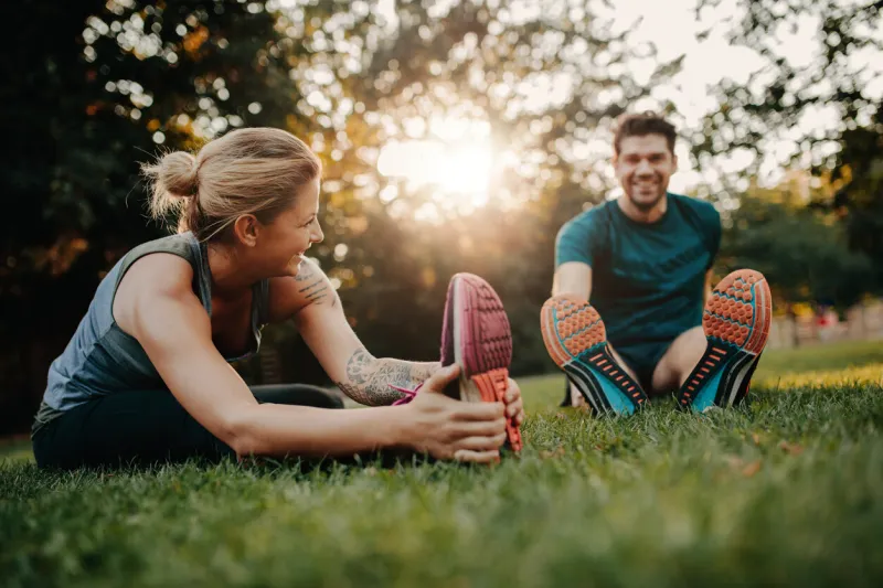 fitness couple stretching outdoors in park young man and woman exercising together in morning
