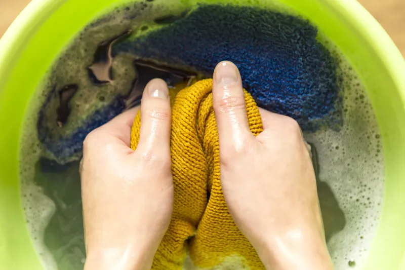 female hands washing color clothes in basin