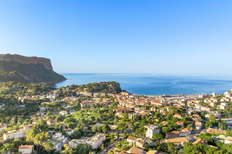 aerial view of cassis, a coastal town in france, with a clear blue sky and the mediterranean sea in the background