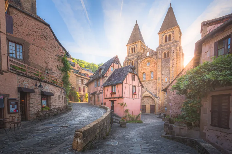 the quaint and charming town centre of the medieval french village conques, aveyron and abbey church of sainte-foy at sunset or sunrise in occitanie, france