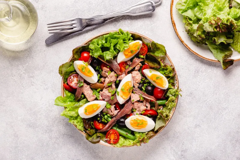 french salad nicoise with tuna, eggs, green beans, tomatoes, olives, lettuce and anchovies