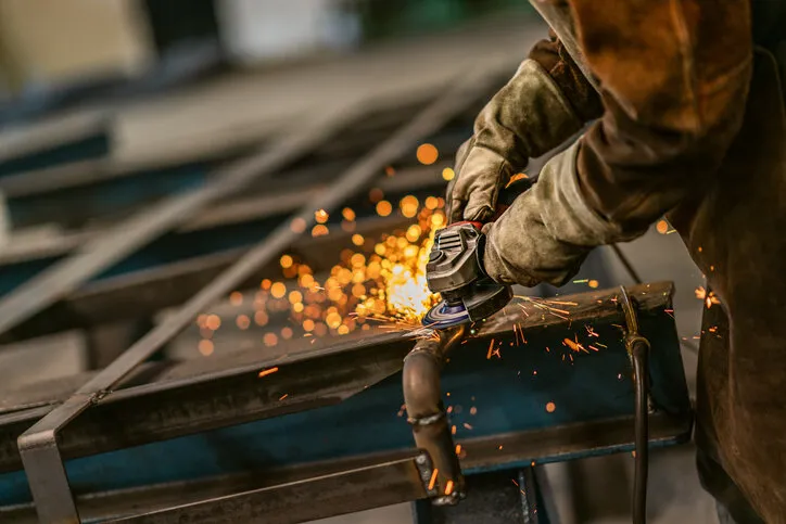 heavy industry worker grinds steel with an angle grinder,sparks flying,close up