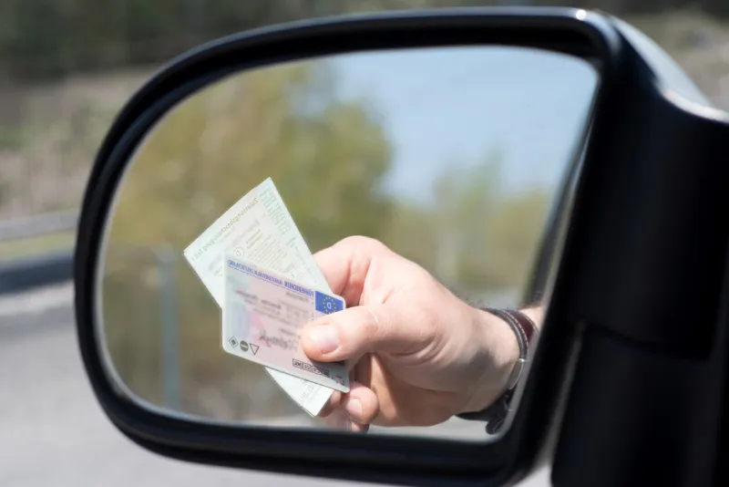 a man shows driver's license and vehicle registration at a check