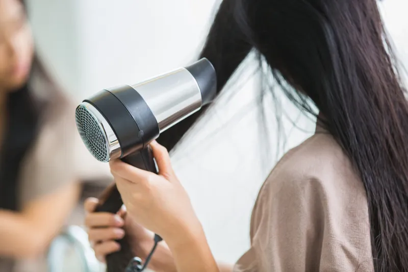 woman with a hair dryer to heat the hair