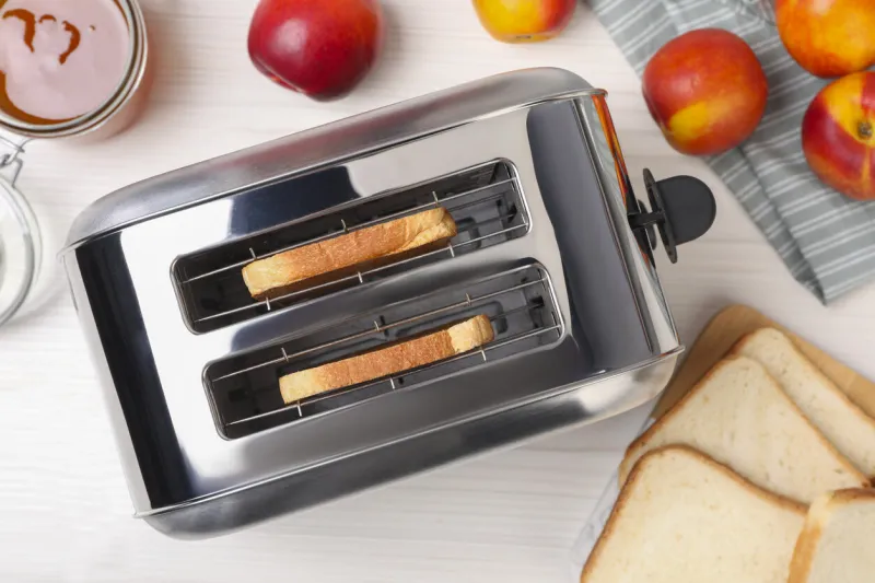 toaster with roasted bread, nectarines and jam on white wooden table, flat lay
