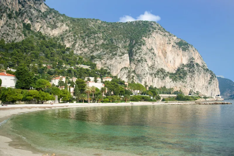 petite afrique beach in beaulieu sur mer on the french riviera with luxury residences and limestone cliffs in the background