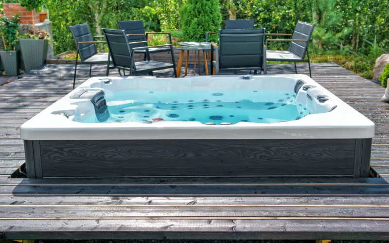 large hot tub embedded in the backyard terrace a sunny summer's day in the shelter of a green garden everyday luxury and relaxation in your own backyard spa complex, vacation and traveling concept