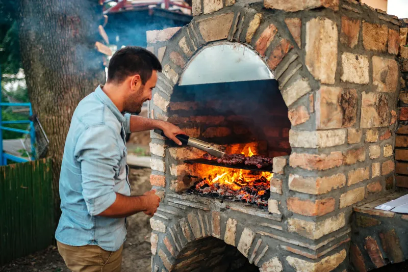 summertime fun young man cooking meat on a brick barbecue