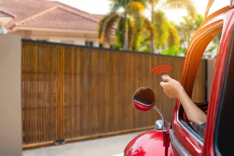 driver hand holding and using remote control to open the electric sliding auto wooden door