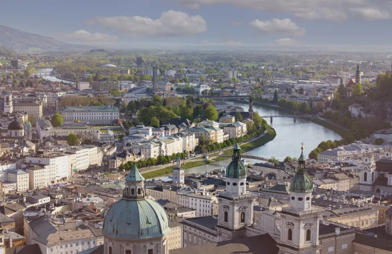 panoramic view in a spring season scene at a historic city of salzburg with salzach river in beautiful golden evening light sky at sunset, salzburger land, austria