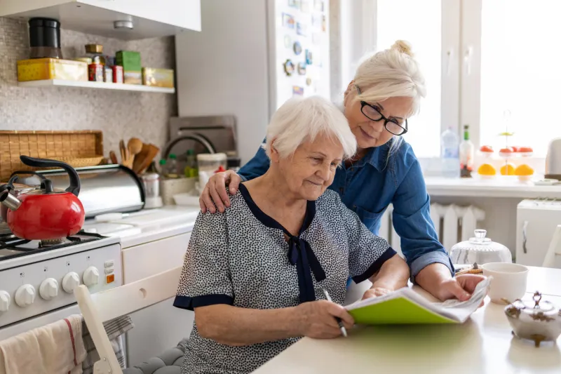 mature woman helping elderly mother with paperwork