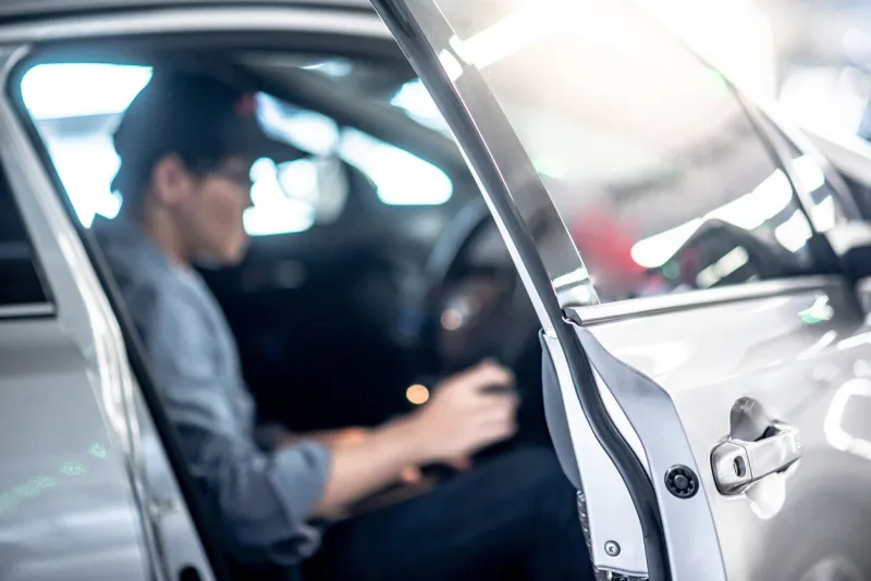 asian auto mechanic sitting on driver seat checking the car in auto service garage mechanical maintenance engineer working in automotive industry automobile servicing and repair
