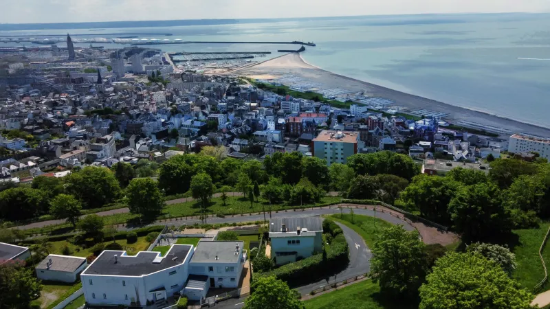 awe drone point of view from hanging gardens of le havre on house and plage (beach) and entrance to port of le havre tall building of lighthouse