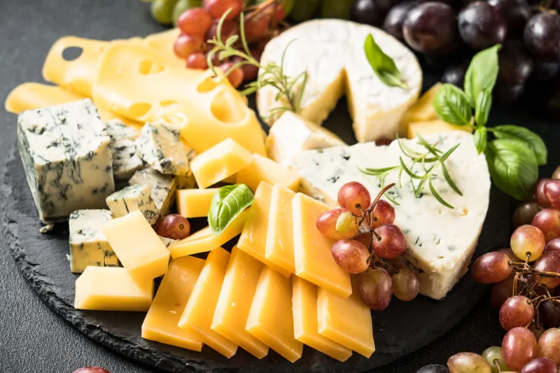cheese platter with craft cheese assortment and grape on slate board