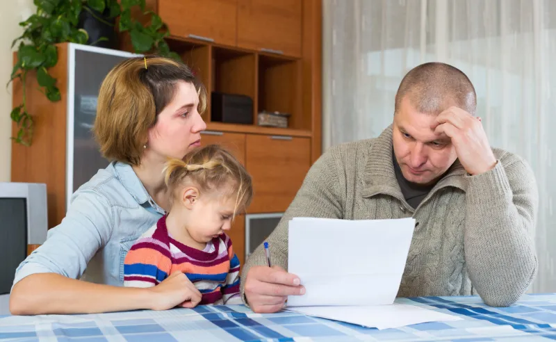 serious couple with little girl counting budget at home