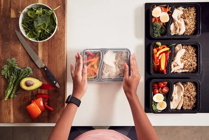 overhead shot of woman preparing batch of healthy meals at home in kitchen