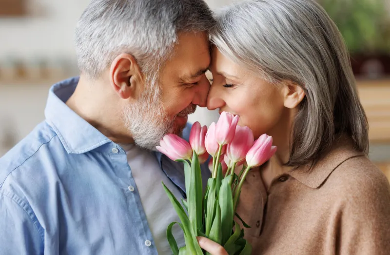 elderly couple in love hugging on valentine's day a loving senior husband gives his wife a tender bouquet of tulip flowers