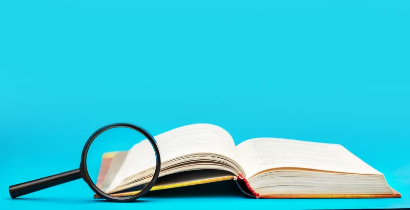 Loupe sur dictionnaire fond bleu