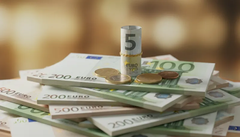 Une photo de quelques pièces d'euros et d'un petit billet, symbolisant les intérêts, posés sur un gr