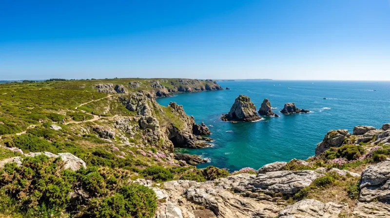 Une photo d'un paysage côtier du Finistère sous un soleil éclatant et un ciel bleu sans nuages