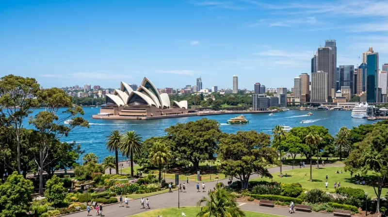 Une photo de l'Opéra de Sydney entouré d'espaces verts urbains sous un ciel dégagé