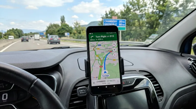 Smartphone sur tableau de bord affichant une application de navigation GPS.