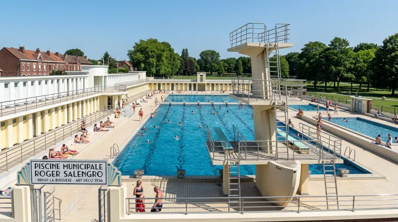 Piscine Art déco ensoleillée avec architecture paquebot et plongeoirs d'époque.