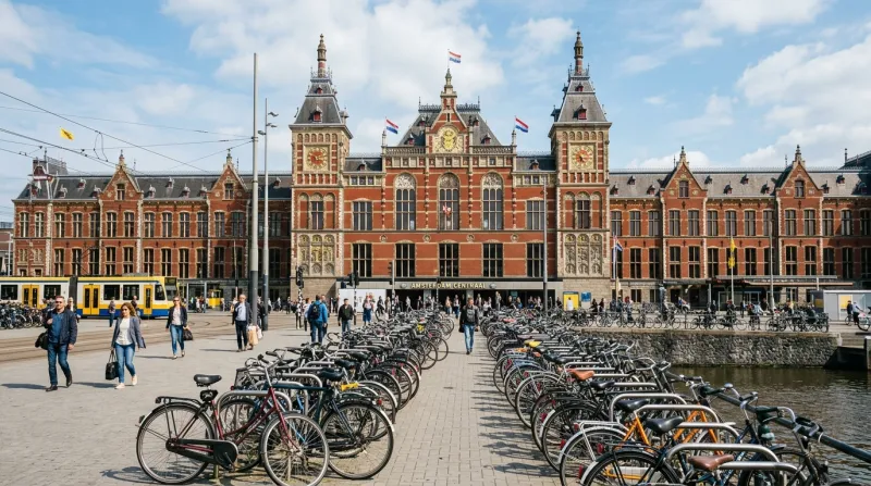 Façade de la gare d'Amsterdam Centraal avec des vélos au premier plan