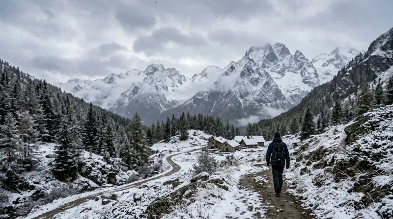 Paysage de montagne sous de légères averses de neige avec sommets enneigés.