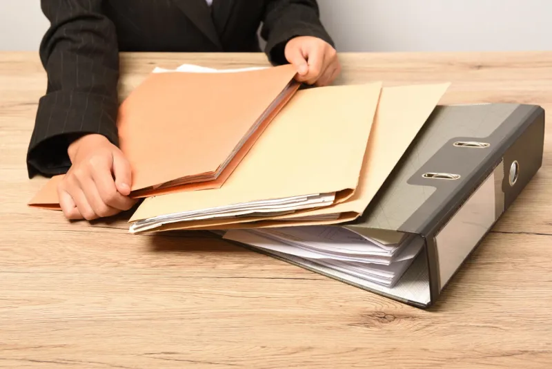 woman hand holding document stacked on desk