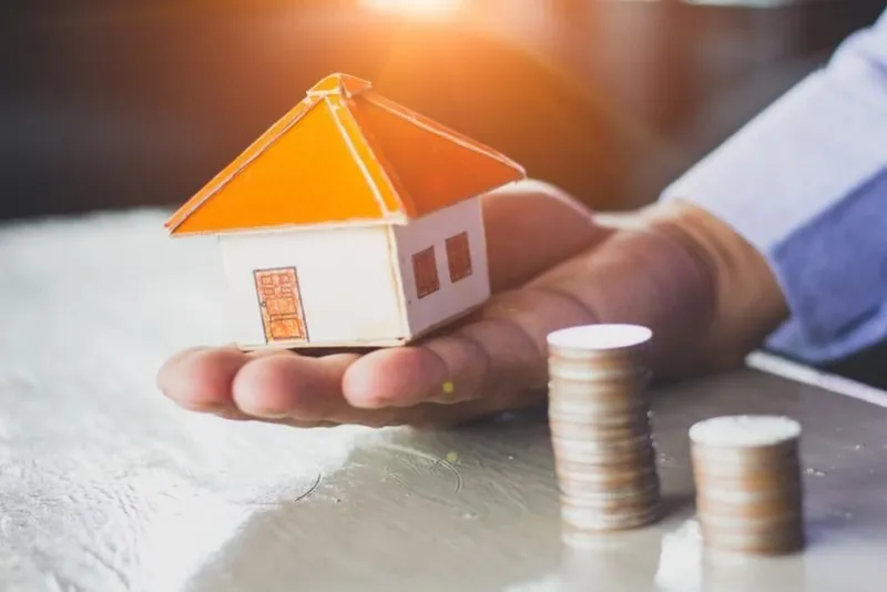 house models and coin in human hands, mortgage concept by money house from the coins