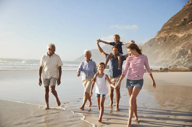 multi generation family on vacation walking along beach together