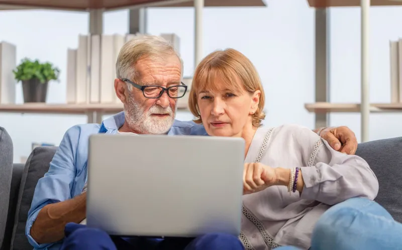 mature woman and senior man using laptop in living room, portrait of worried senior couple checking their bills and work on netbook read document information at home