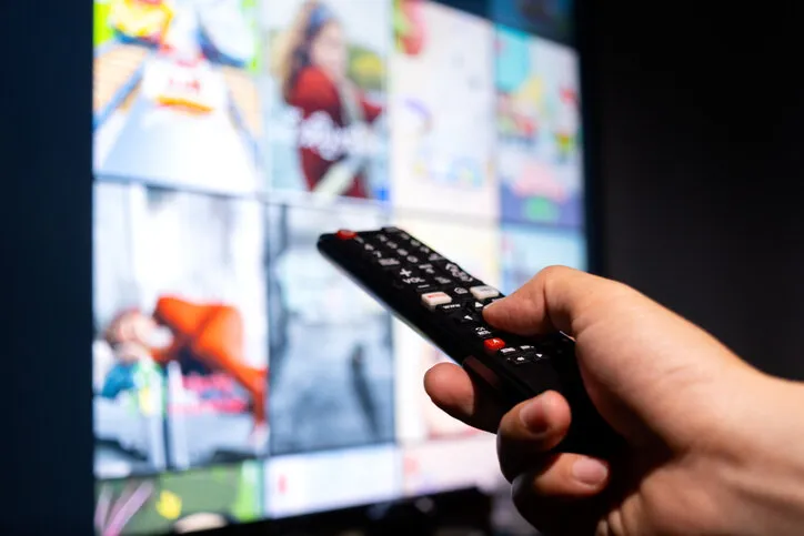 man's hand holding a remote control, multimedia, online tv, broadcasting entertainment to viewers at home the idea behind the broadcast
