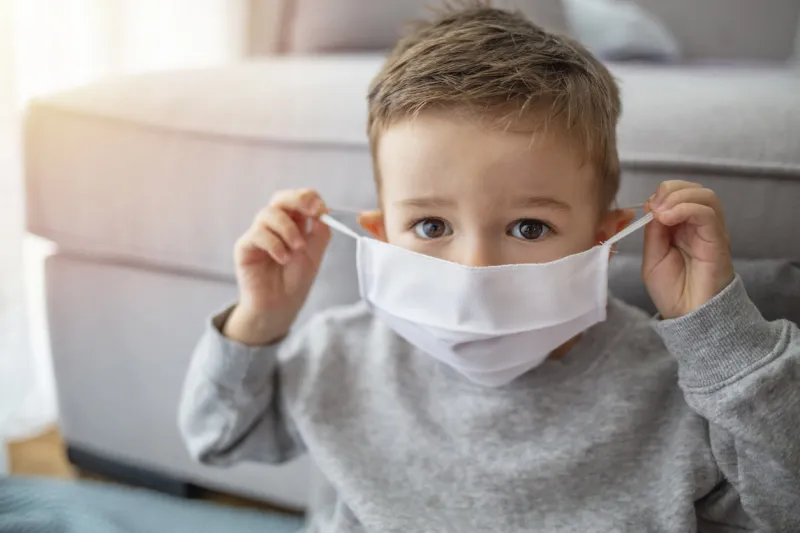 young child wearing a respiratory mask as a prevention against the coronavirus covid-19 little boy wearing anti virus mask staying at home protection against flu and virus infection