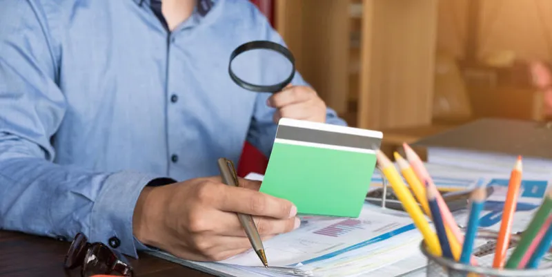 an auditor hand holding magnifying glass over saving account passbook for looking and analysis financial data, business finances and saving concept
