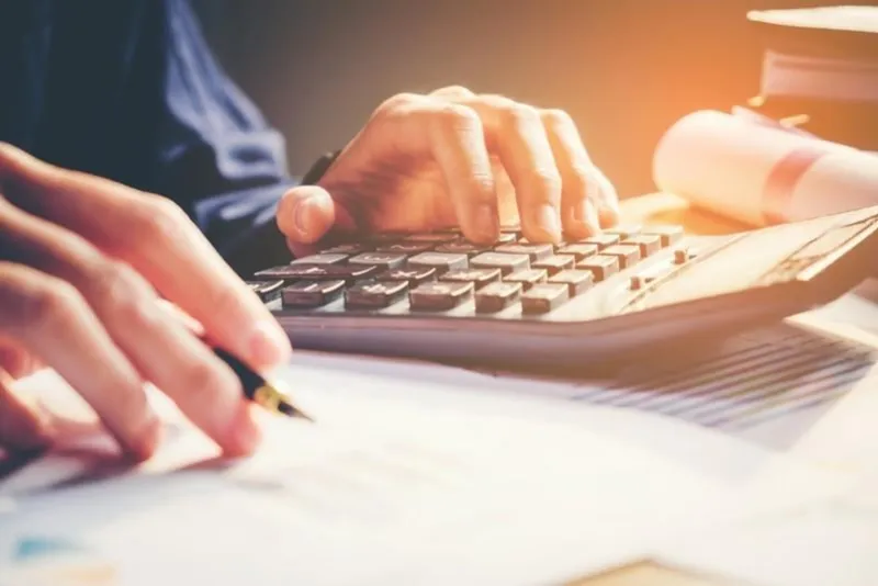 businessman's hands with calculator at the office and financial data analyzing counting on wood desk