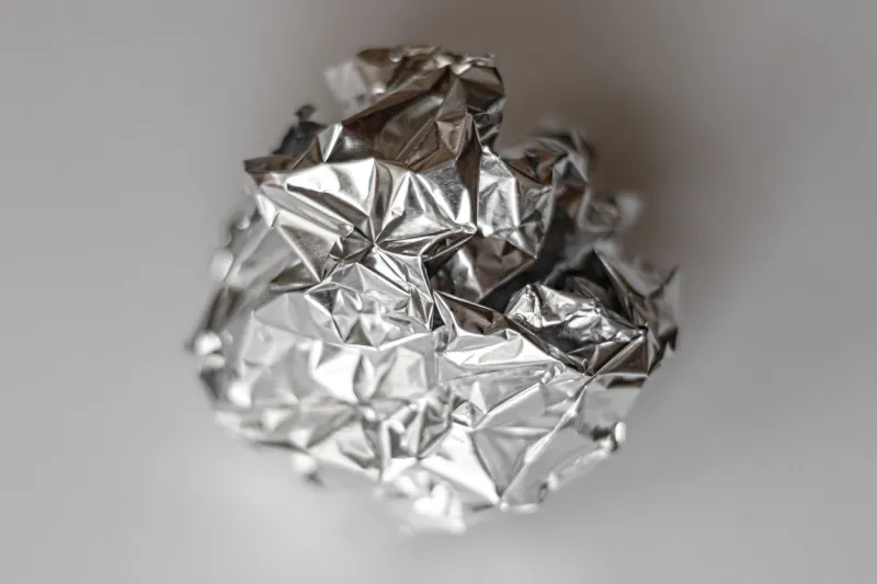 ball of crumpled silver color foil close up on gray background