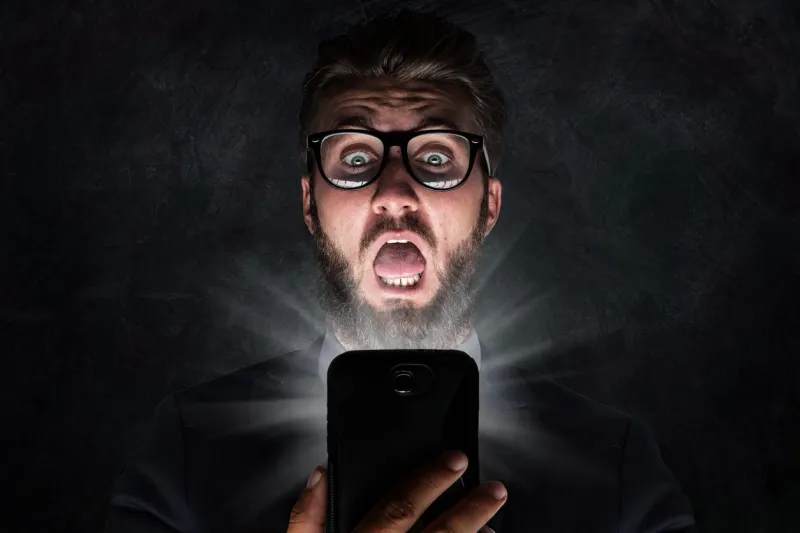 nerd with glasses is shocked after reading a sms